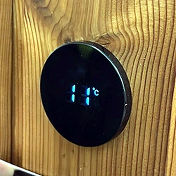 Digitalni termometer na lesenem obodu vroče kadi.